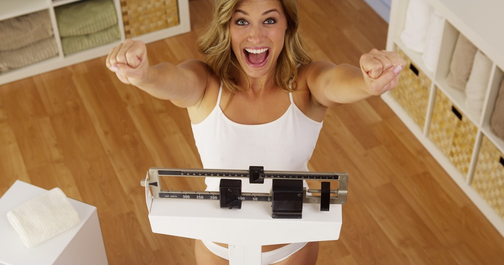 Patient celebrating weight loss on a scale at Belle Medical.